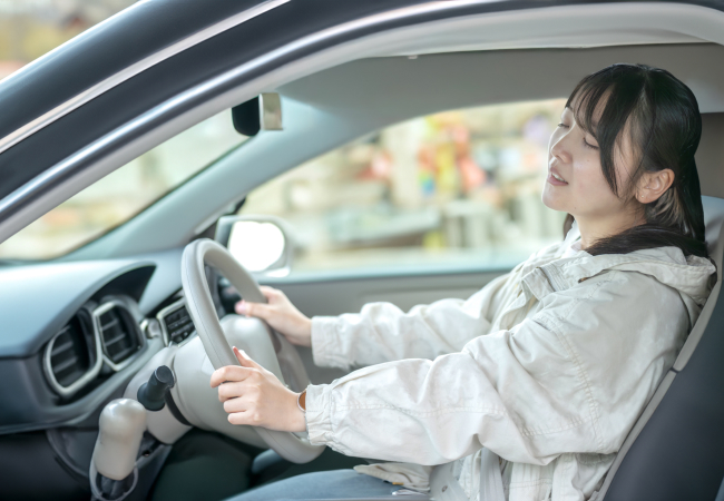 苦しい顔で運転をする若い女性