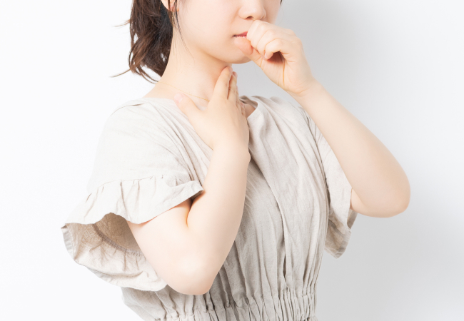 喉に手を当てる女性