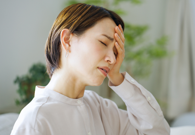 頭に手を当て苦しそうな表情の女性