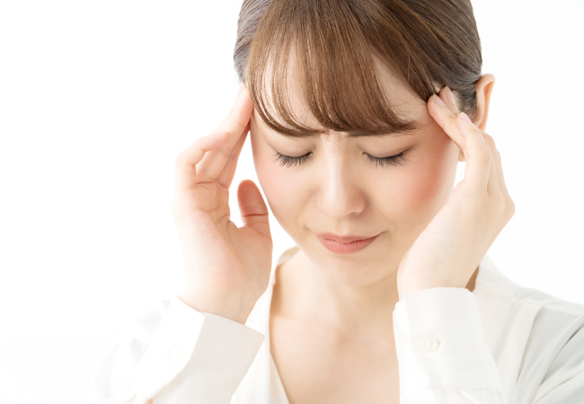 頭に手を当て苦しそうな表情の女性